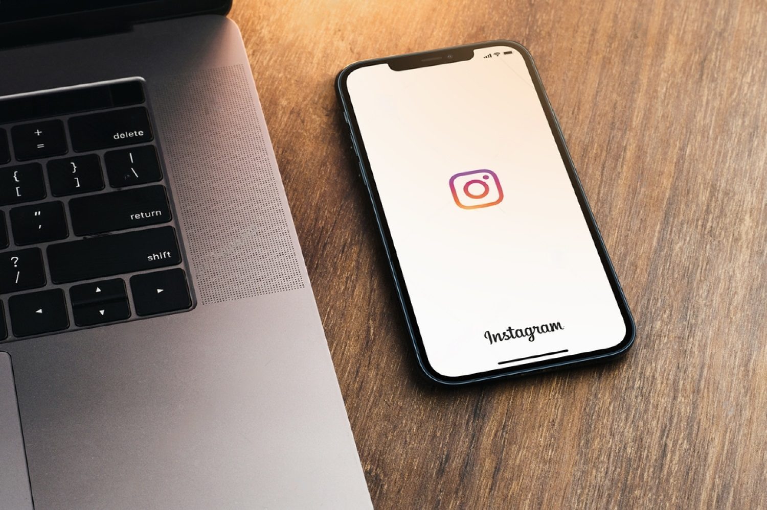 Metade de um laptop e um smartphone em cima de uma mesa, demonstrando marketing nas redes sociais.