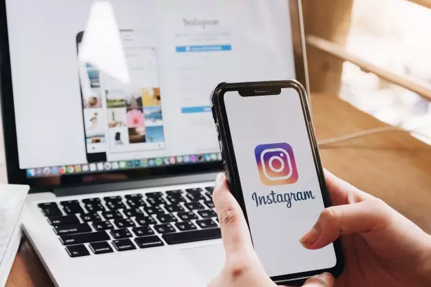Marketing jurídico no instagram, pessoa segurando o celular na frente de um computador