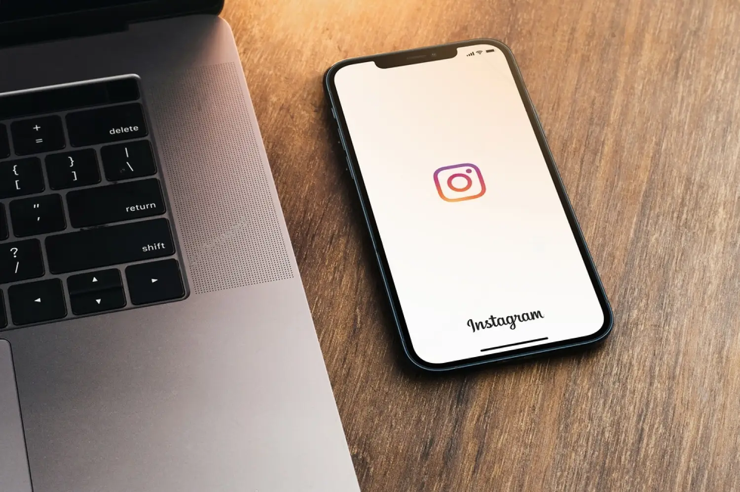 Metade de um laptop e um smartphone em cima de uma mesa, demonstrando marketing nas redes sociais.